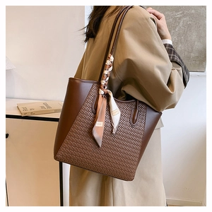 Detail of leather tote bag with woven panel and decorative silk scarf on handle