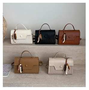 Structured woven crossbody bags in five colors displayed on minimalist stone stairs