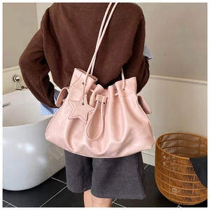 Detail of light pink drawstring bucket bag with star tag and litchi grain leather texture