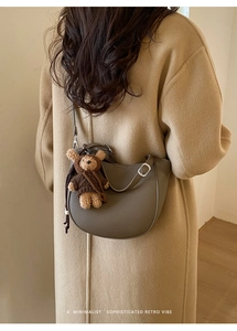 Detail of grey pebbled leather hobo bag with adjustable strap and plush bear charm