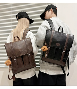 Detail of vintage PU leather backpacks in black and brown with plush bear charms