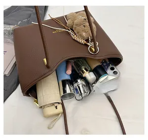 Spacious interior of a brown leather tote bag holding a tablet, umbrella, and cosmetics