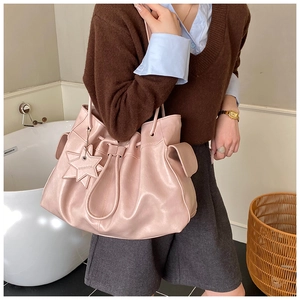 Detail of light pink pleated tote with side pockets and star pendant on model