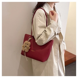 Detail of burgundy pebbled leather tote bag with gold lettering and cute dog charm