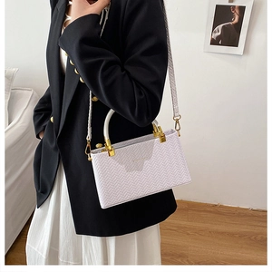 Close-up of lilac woven texture handbag featuring gold hardware and white handles