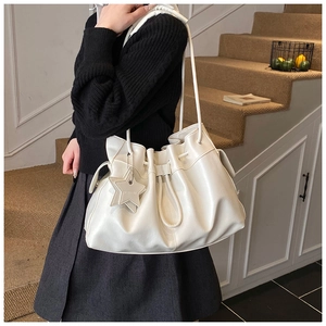 Macro view of white pleated leather tote bag featuring a star charm and drawstring detail