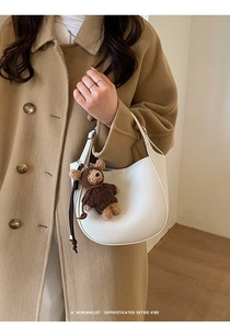 Close-up of white pebble grain leather hobo bag with cute brown knitted bear charm detail