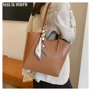 Detail of woven brown leather tote bag with decorative fashion scarf on the handle