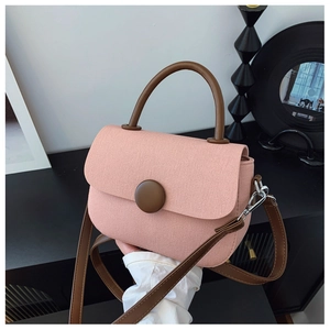 Detailed shot of pink canvas texture and dark brown leather strap on a small crossbody bag