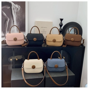 Group shot of retro crossbody bags in six colors with leather handles on a black counter