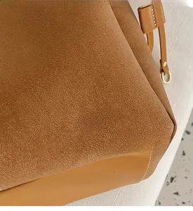 Detail of brown suede and smooth leather tote bag with gold logo text and ring hardware