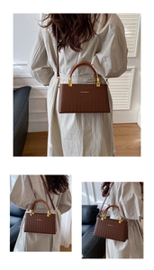 Close-up of brown woven texture PU leather bag with elegant golden metal buckles
