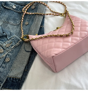 Détail du sac demi-lune rose matelassé avec chaîne dorée sur fond de denim