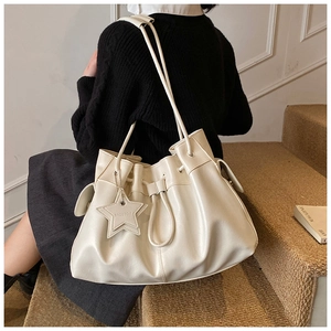 Detail of white pleated leather tote with star charm and embossed brand lettering