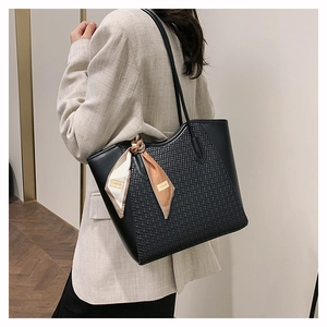 Close-up of black woven tote bag with silk scarf accessory worn over the shoulder
