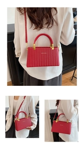 Detail of red woven texture handbag featuring gold hardware and a metal twist lock