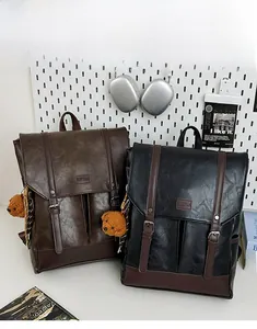 Detail view of vintage leather texture and buckle straps on dual backpacks with bear charm