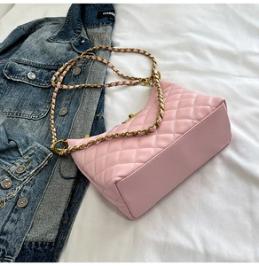Détail d'un sac rose matelassé avec bandoulière en chaîne dorée sur drap blanc