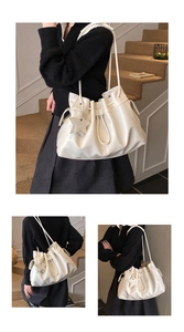 Detail of a beige drawstring bucket bag featuring a star pendant and soft PU leather texture