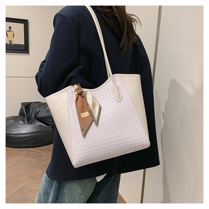 Detail of woven texture on a large cream tote bag with silk scarf on model