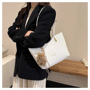 White pebbled leather tote bag detail with plush bear charm and fashion lettering