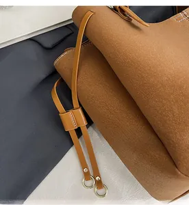 Detail view of brown pebbled leather texture with white stitching and gold metal hardware