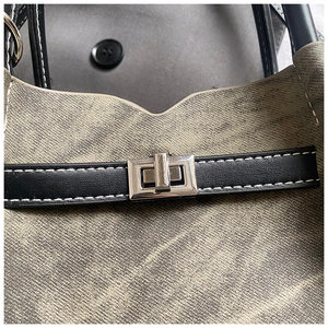 Macro shot of grey twill fabric texture with silver turn-lock and black leather trim details