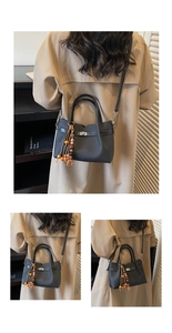 Détails d'un sac cabas en similicuir noir avec fermoir rotatif argenté et pompon perlé