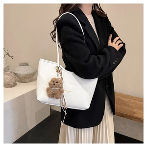 Detailed side view of white lychee pattern leather tote bag with brown bear pendant