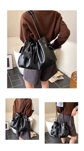 Detail of black drawstring bucket bag with star charm and long shoulder straps