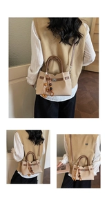 Détail d'un sac à main en toile beige avec fermoir en cuir et pendentif à pampilles
