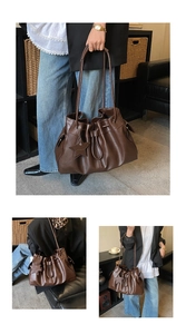 Detail of dark brown drawstring bucket bag with star pendant and pleated leather finish