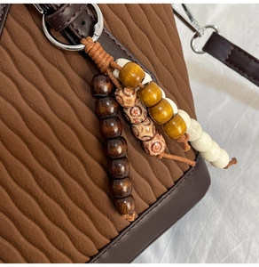Détail du sac à bandoulière marron plissé avec breloques en perles de bois colorées