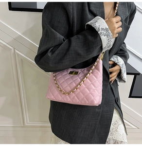 Gros plan sur un sac hobo matelassé rose avec chaîne dorée et fermoir rotatif carré