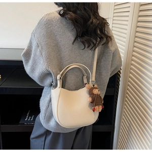 Detailansicht der cremefarbenen Lederhandtasche mit süßem Bärenanhänger-Detail