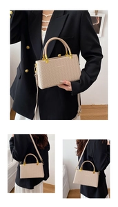 Detail of beige woven tote bag featuring gold hardware and circular top handles