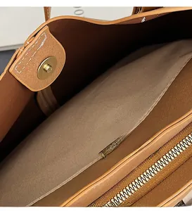 Detailed macro of golden magnetic closure and metallic zipper on brown leather tote