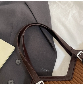 Détail d'un sac seau vintage en tissu plissé marron avec bandoulière en cuir et boucle argent