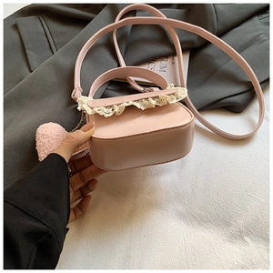 Détail d'un sac bandoulière rose avec bordure en dentelle et pendentif cœur