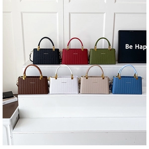 Multiple colors of woven texture tote bags displayed on minimalist white stairs