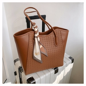 Detail of woven texture on brown tote bag with decorative fashion scarf and smooth handle