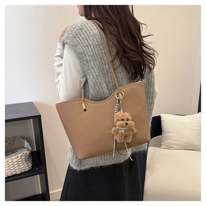Brown lychee leather tote bag with plush puppy charm shown from a side back view