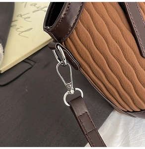 Détail de la texture cuir marron plissé et finitions métalliques d'un sac seau