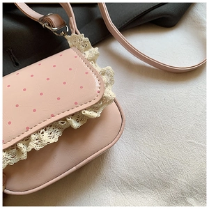 Détail d'un sac rose à pois rouges avec des finitions en dentelle multicouche