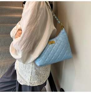 Détail d'un sac matelassé bleu clair avec chaîne dorée et fermoir métallique élégant