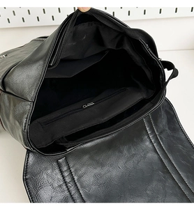 Internal view of the black leather backpack showing the main compartment and zipper pocket