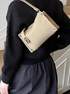Minimalist beige lychee grain leather crossbody bag with silver studs on a female model