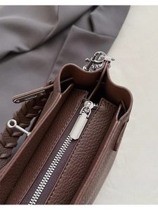 Détail du sac seau en cuir marron avec fermeture éclair argentée et anse tressée