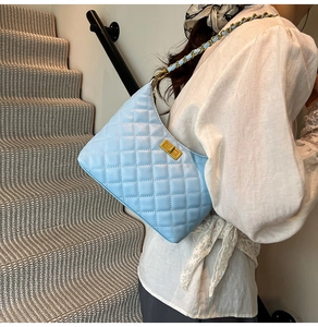 Détail d'un sac bandoulière matelassé bleu clair avec chaîne dorée et fermoir pivotant
