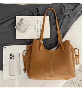 Flat lay of brown suede tote bag with daily essentials for office and commute use